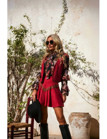 Chaleco Briar Camaleónica by Capriche, ante burdeos con tachuelas doradas, conjunto con blusa Trovan y falda Solvik