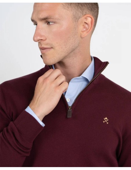 Detalle del cuello con cremallera y logo dorado del jersey granate
