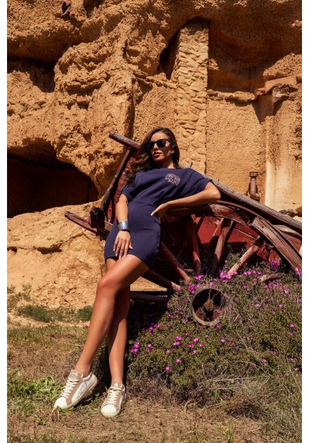 Vestido Aven Camaleónica by Capriche, pose recostada entre piedra y madera