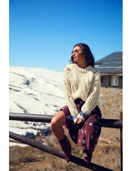 Ropa Camaleónica: jersey Roamer de punto crudo sentada en valla con falda estampada